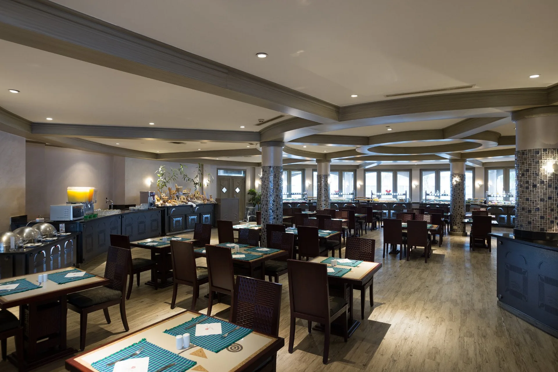 Sala ristorante con tavoli in legno, tovagliette verdi e zona buffet