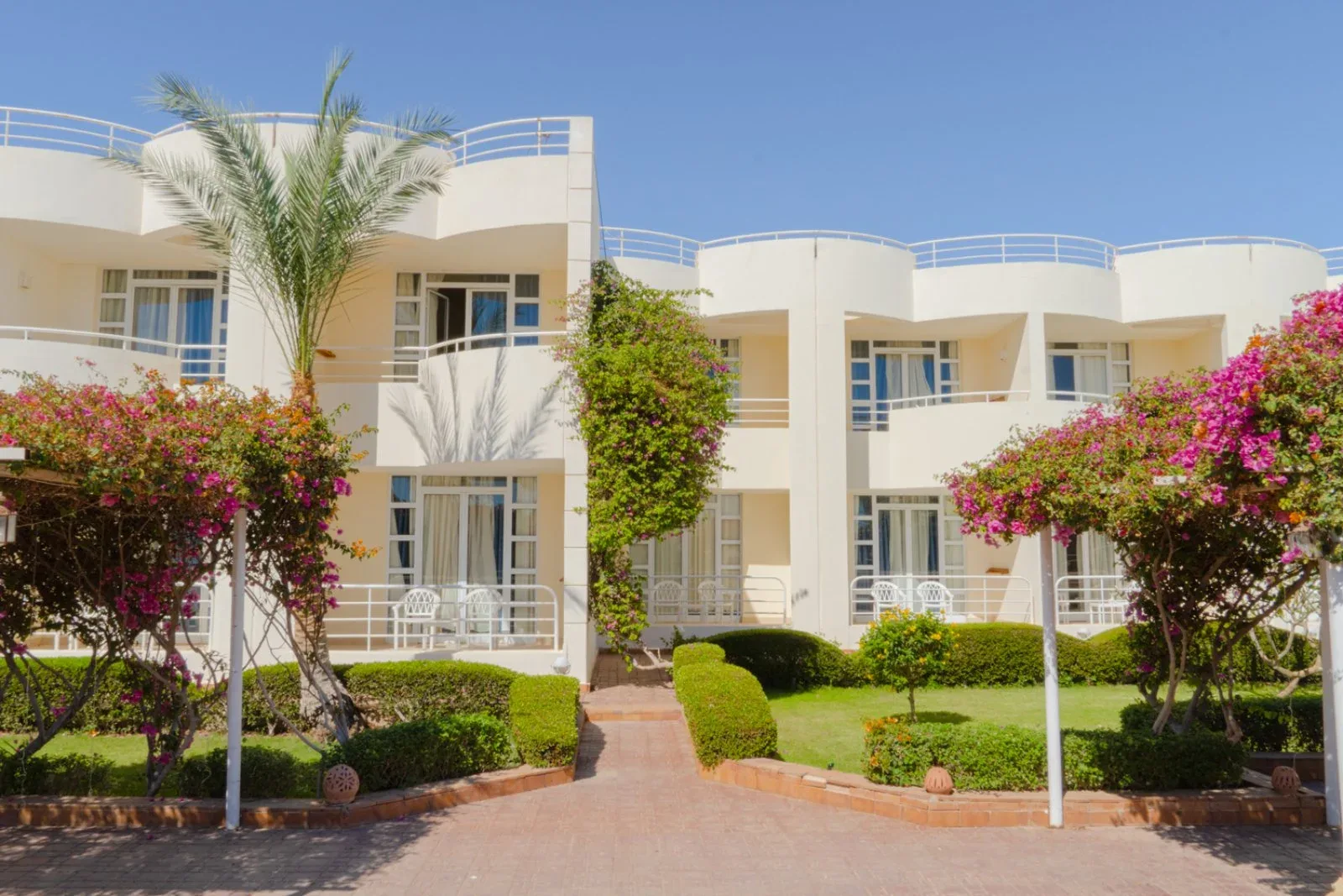 Facciata degli edifici bianchi del resort con giardino e bougainvillea fiorite