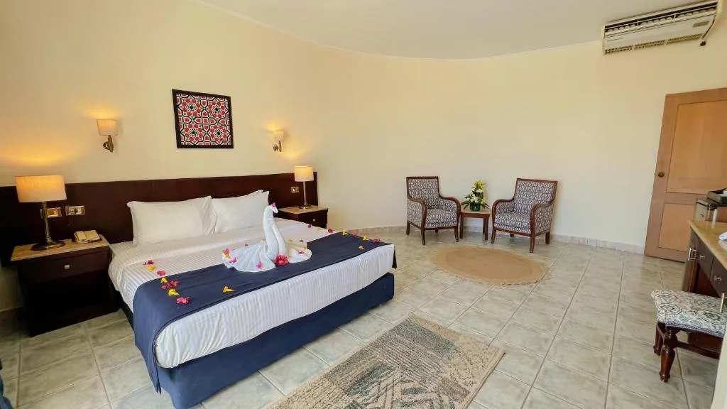 Ampia camera con letto matrimoniale decorato a cigno, poltrone e area salotto