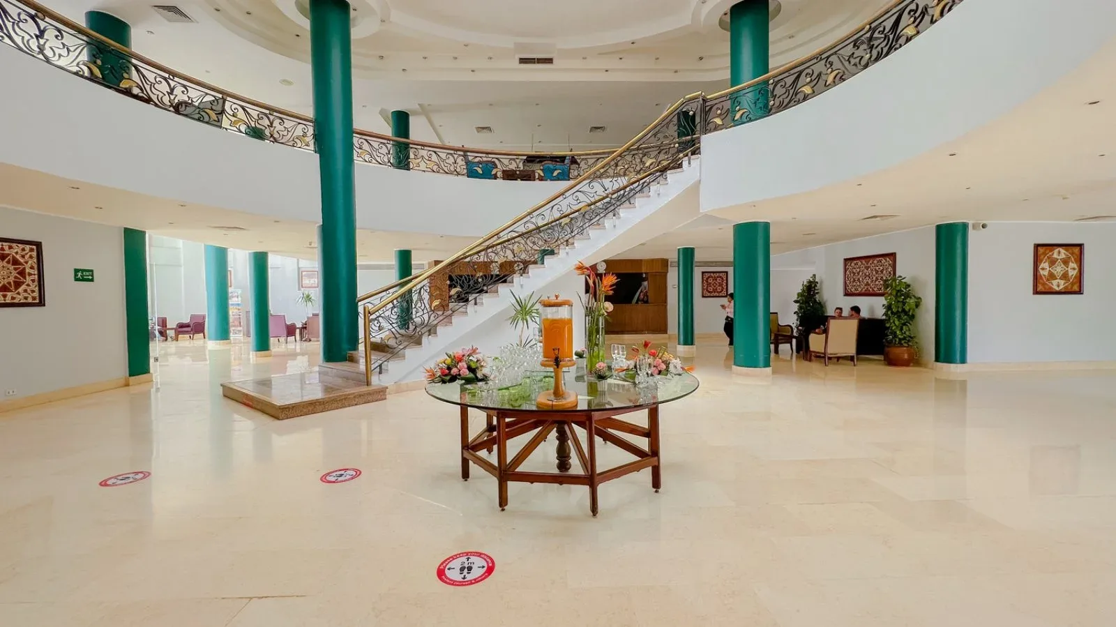 Ampia hall dell'hotel con scala elegante, colonne verdi e pavimento in marmo
