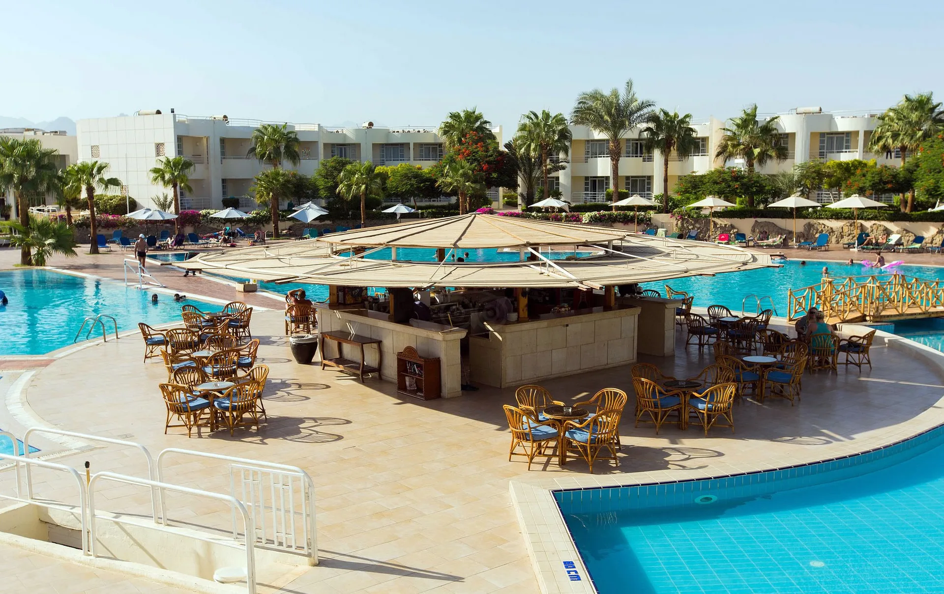 Bar centrale della piscina con tavoli e sedie in rattan e tettoia circolare